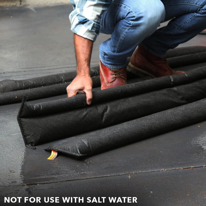 Placing Quick Dam Flood Barriers on wet ground to block water showing proper setup and warning not for use with salt water.