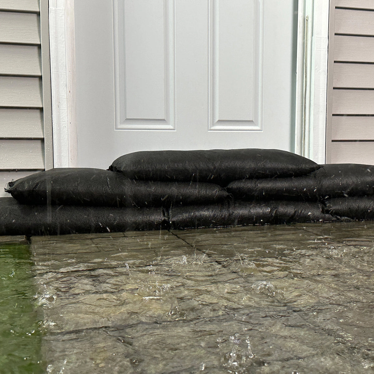 Quick Dam Flood Bags expanded with water protecting a home entryway from flooding redirecting and containing water.