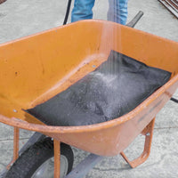 Pre-activating a Quick Dam Flood Bag in a barrel with a hose showing how the bag absorbs water and expands before flood protection use.