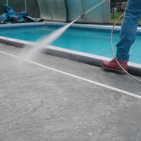 Quick Dam Flood Barrier placed along a pool edge blocking water from entering the pool while the deck is being cleaned with a hose.
