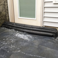 Quick Dam Flood Barriers stacked at a doorway blocking and diverting rushing water to protect a home from flooding.