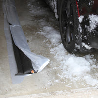 Quick Dam Flood Barrier placed inside a garage door next to a car with melting snow showing how it blocks water and slush from entering.