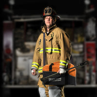 Firefighter carrying a Quick Dam Flood Control duffle bag kit for emergency flood response and rapid deployment.