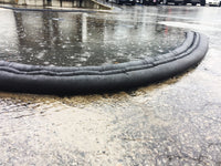 Quick Dam Flood Barriers creating a curved perimeter to block pooling rainwater in a parking lot, providing reliable flood protection and water diversion.