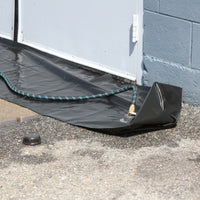 Quick Dam Water Curb being filled with a garden hose at a building entrance, creating a reusable water-filled flood barrier for door protection.