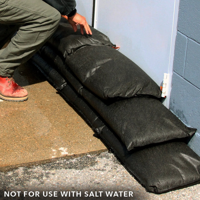 Stacked Quick Dam Flood Bags arranged in a brick pattern to build a taller barrier against water intrusion.