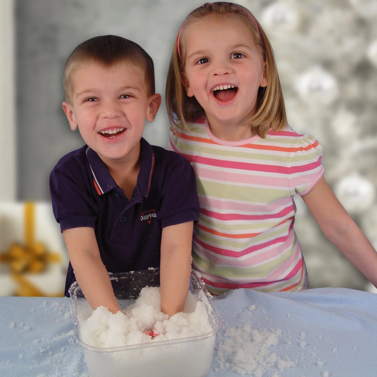 Two children playing with snow indoors, smiling and having fun.