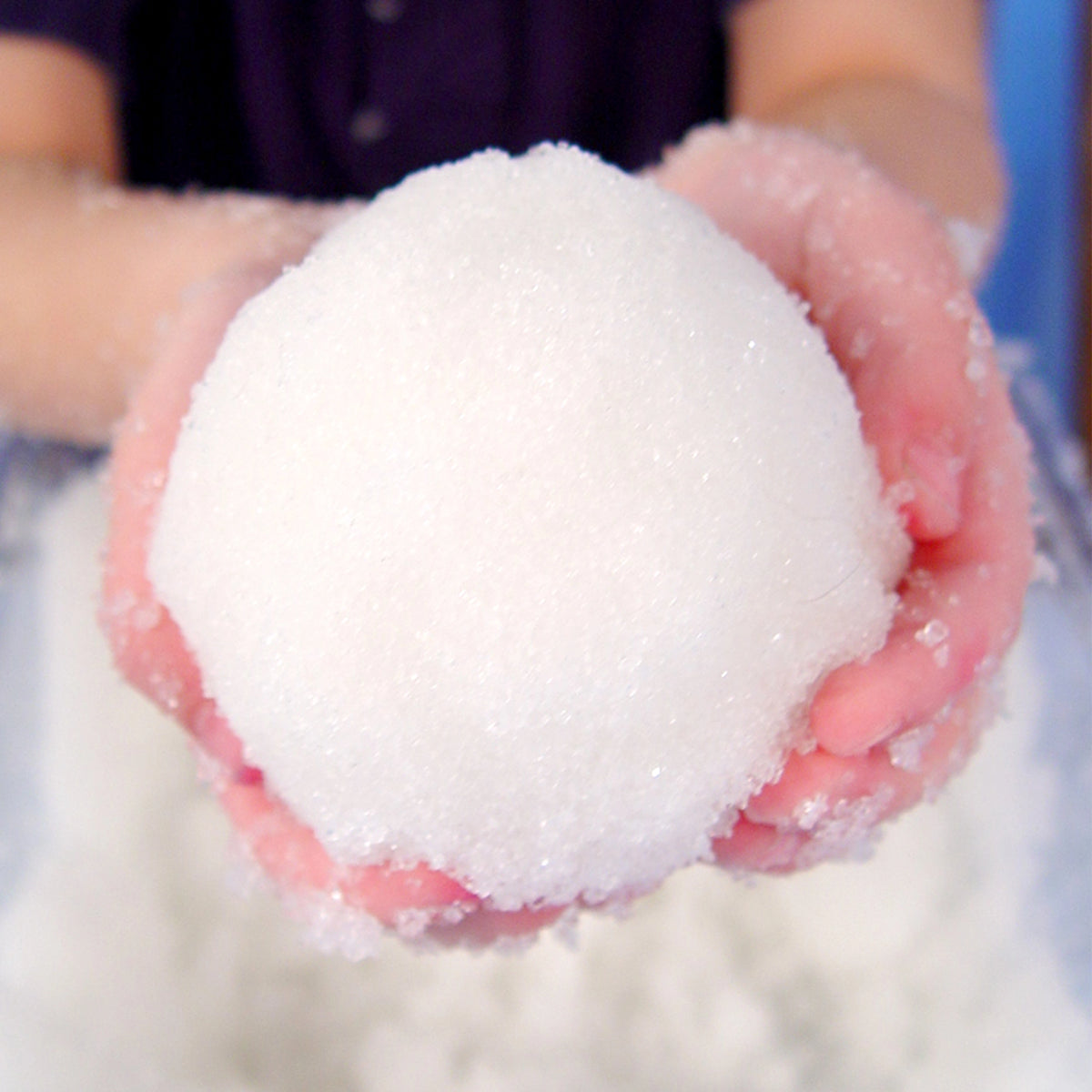 Hand holding a snowball with a blurred background