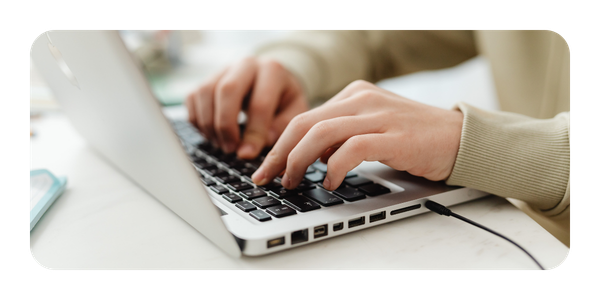 Close-up of hands typing on a laptop keyboard