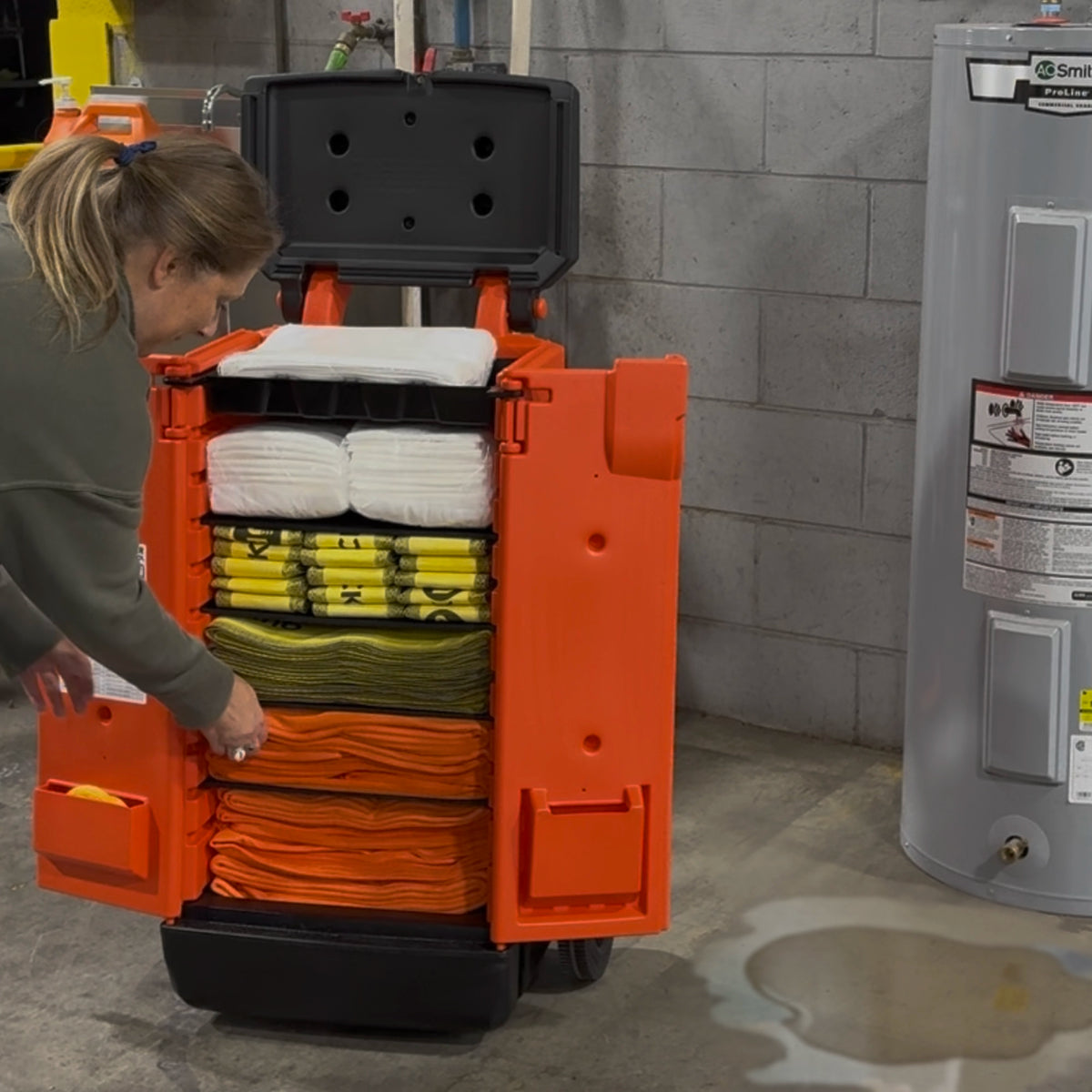 Person interacting with a mobile storage cart filled with flood supplies in an industrial setting.