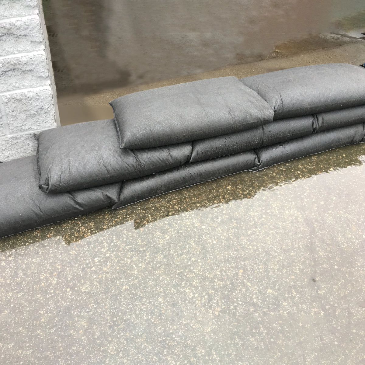 Stack of black flood bags on a concrete surface protecting a garage opening