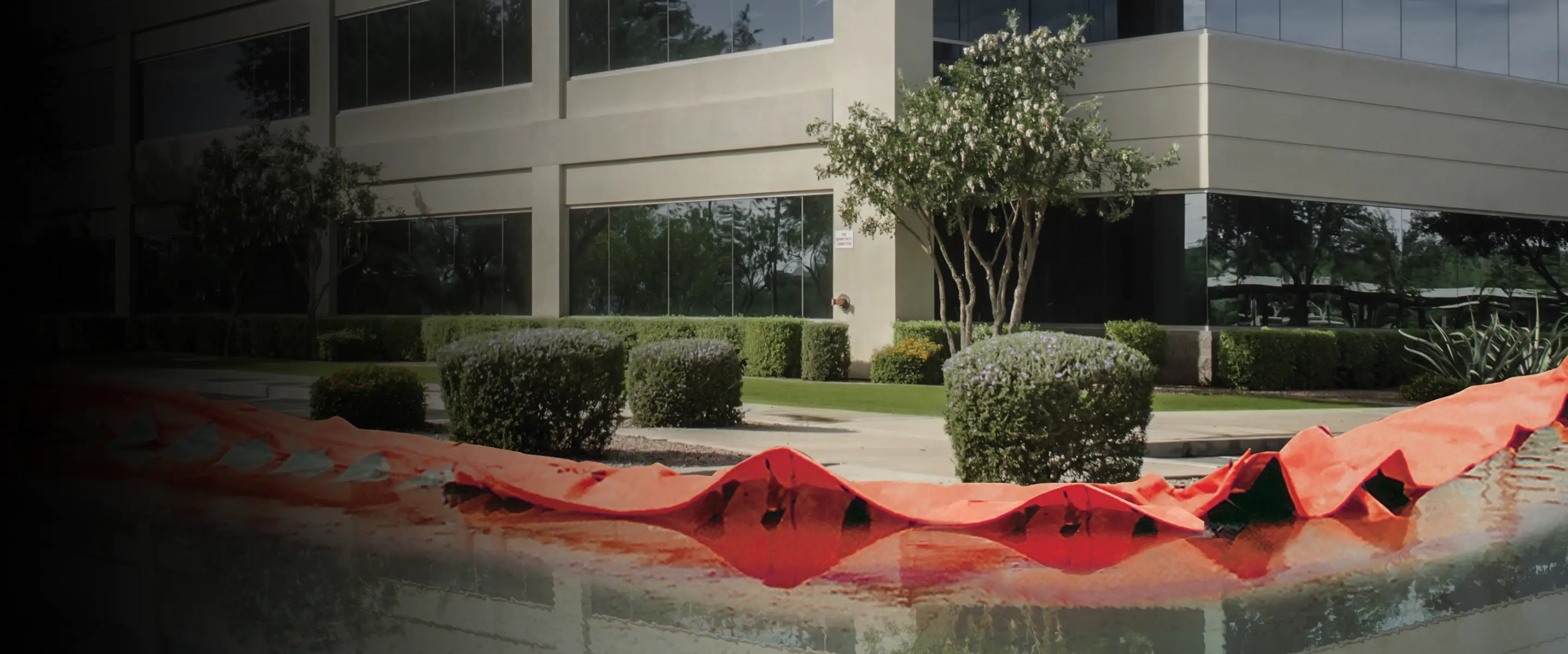 Orange water force in front of a building with greenery