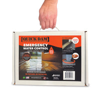 A hand holding a white cardboard box for Quick Dam Emergency Water Control, showing the front and side labels of the product packaging.