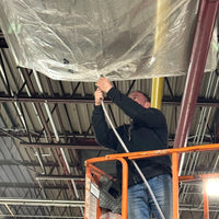 Person on a lift hanging a Quick Dam Leak Diverter in an industrial setting