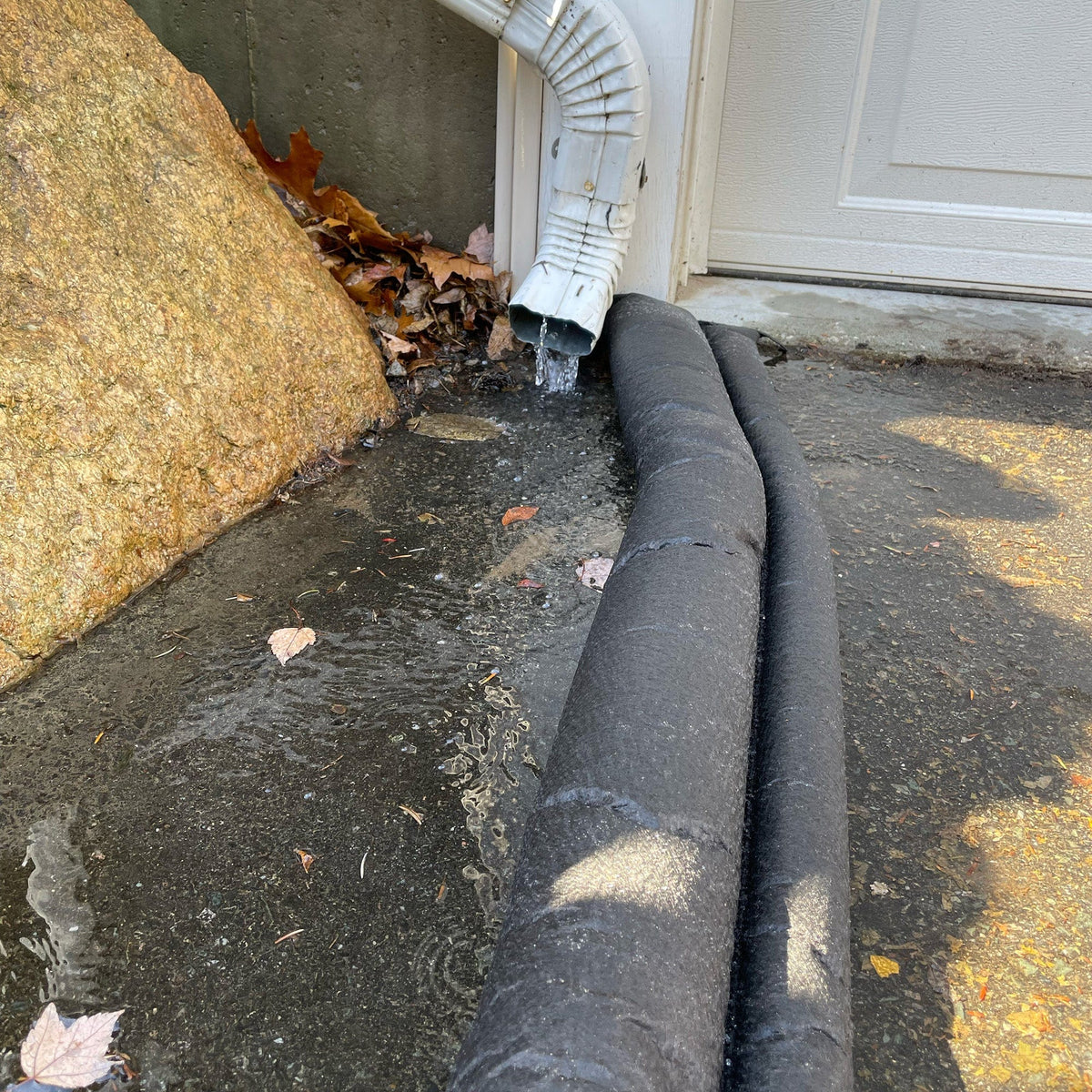 Gutter with downspout and connected drain pipe on a concrete surface