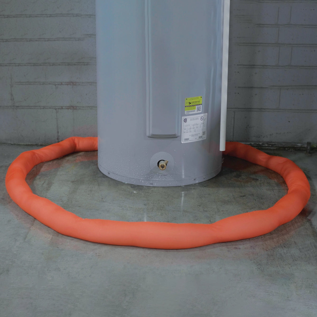 water heater with orange water dam on a concrete floor against a brick wall