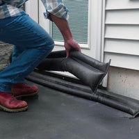 Person installing flood barriers to a doorway on a house exterior