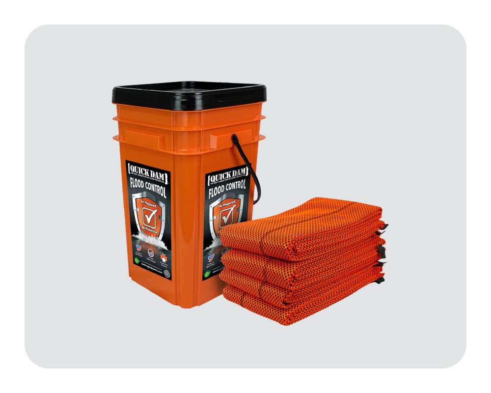 Orange flood control bucket with a stack of orange flood barriers on a white background