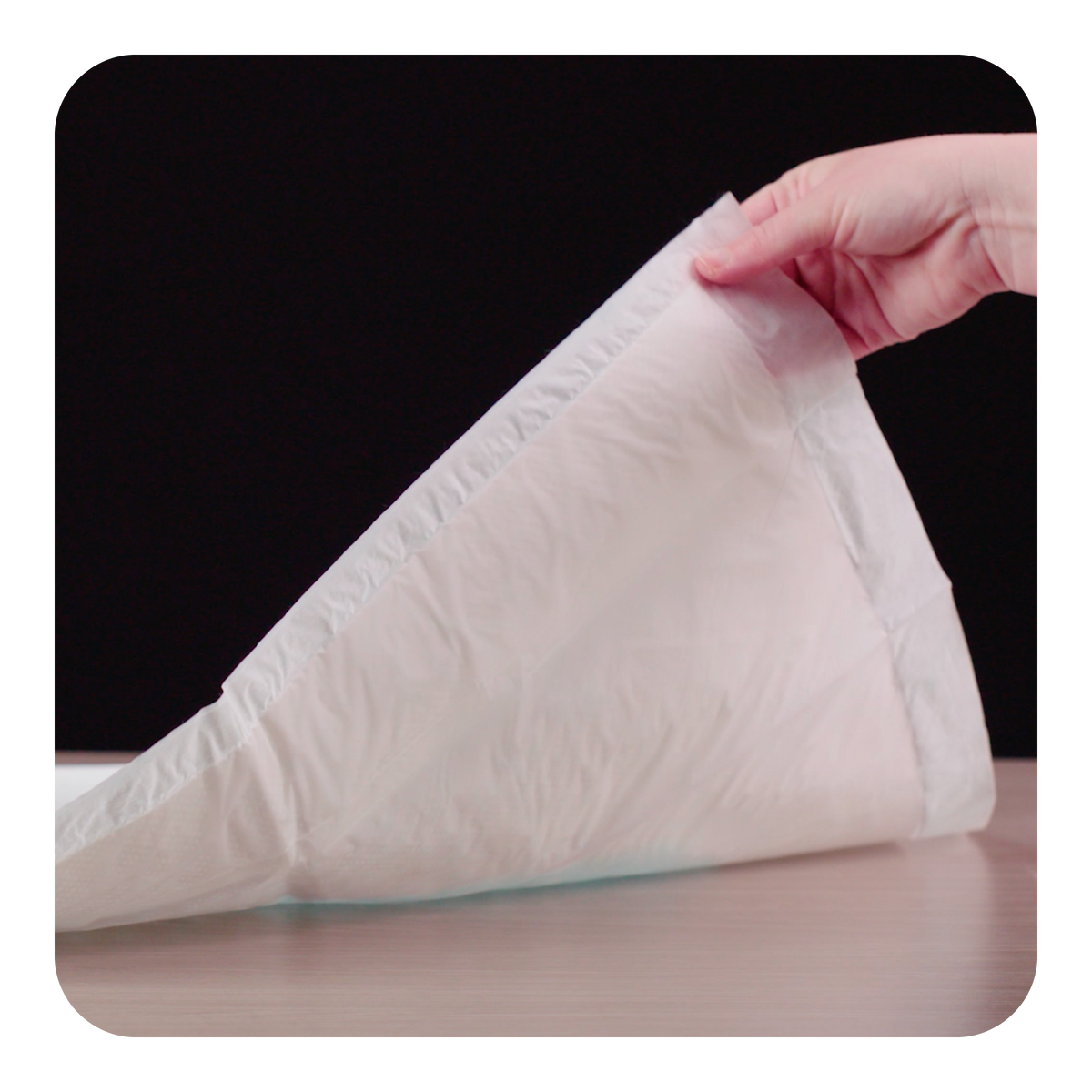 Person holding a white drip mat against a black background