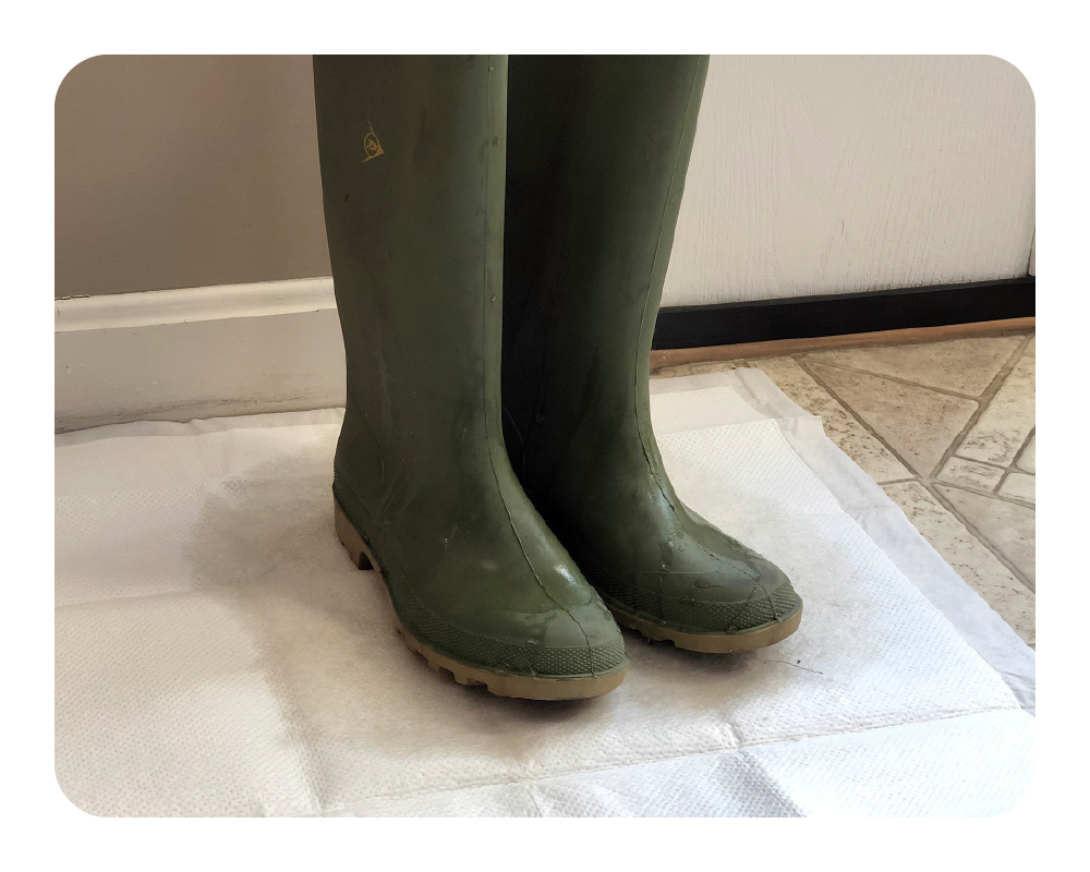 Green rubber boots on a quick dam drip mat