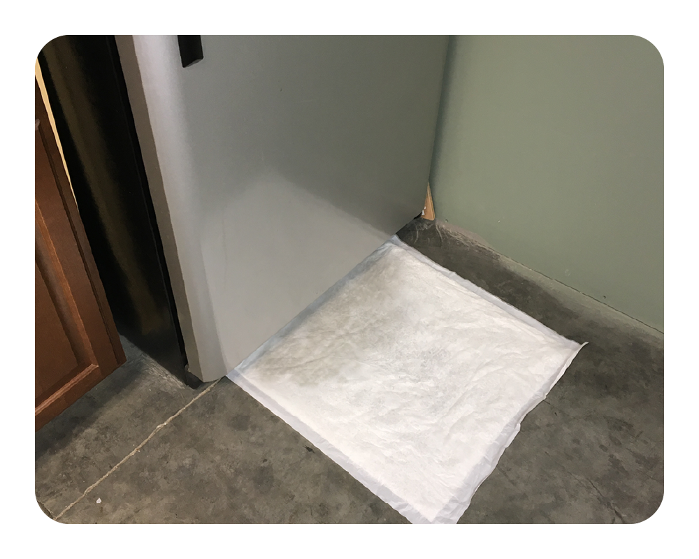 Quick Dam drip mat on the floor under a leaky fridge
