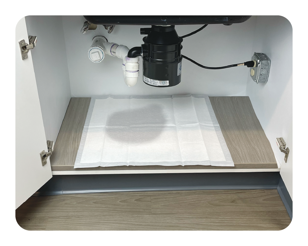 Under-sink kitchen plumbing system with a drain and filter on a white quick dam drip mat