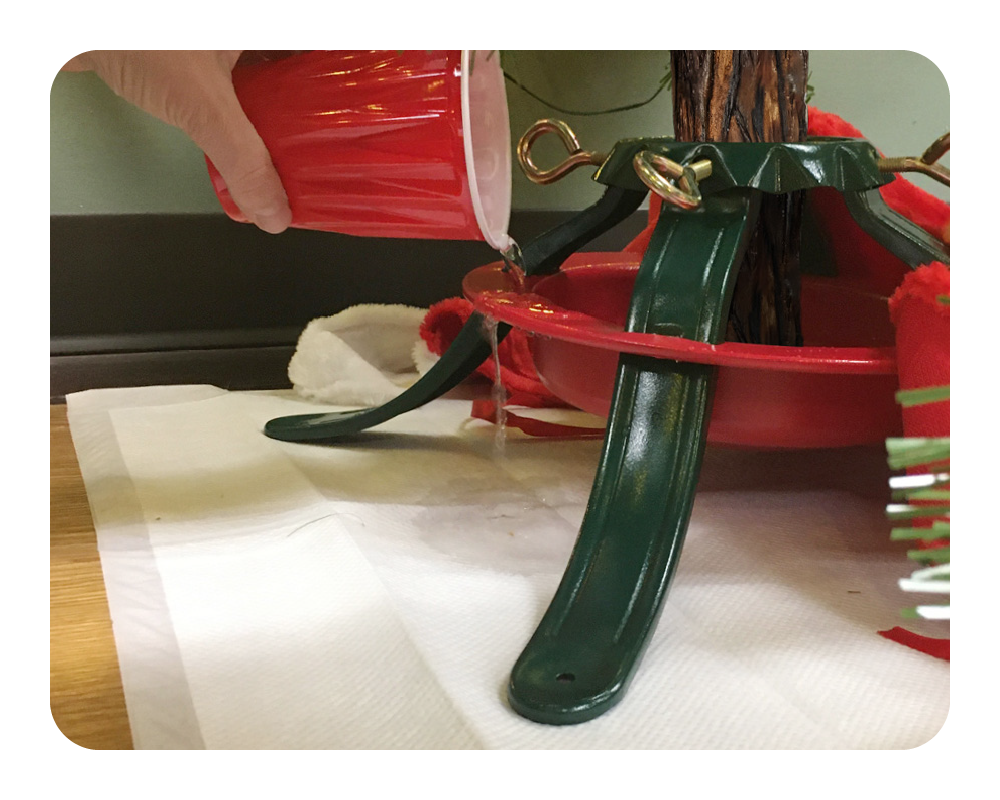 Quick Dam drip mat under a red and green Christmas tree stand