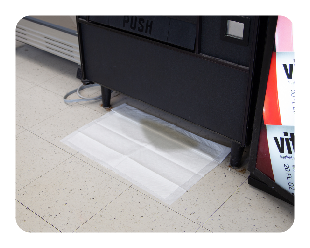 Quick Dam drip mat on a tiled floor next to a black appliance with 'PUSH' label.