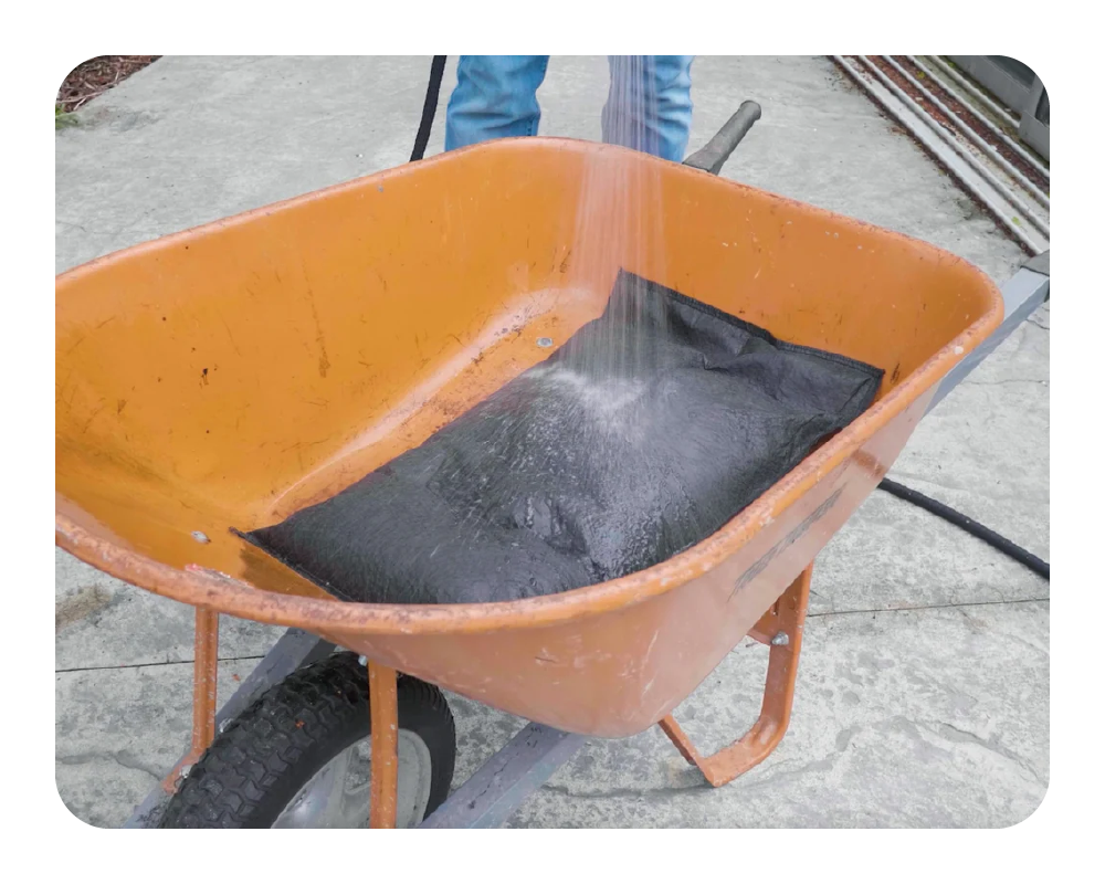Man activating black flood bag in a wheelbarrow