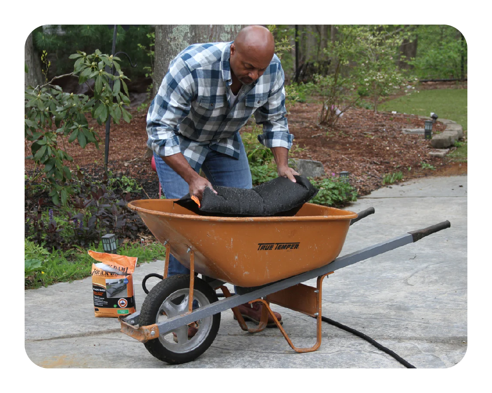 Man removing flood bag from a wheelbarrow in a backyard setting