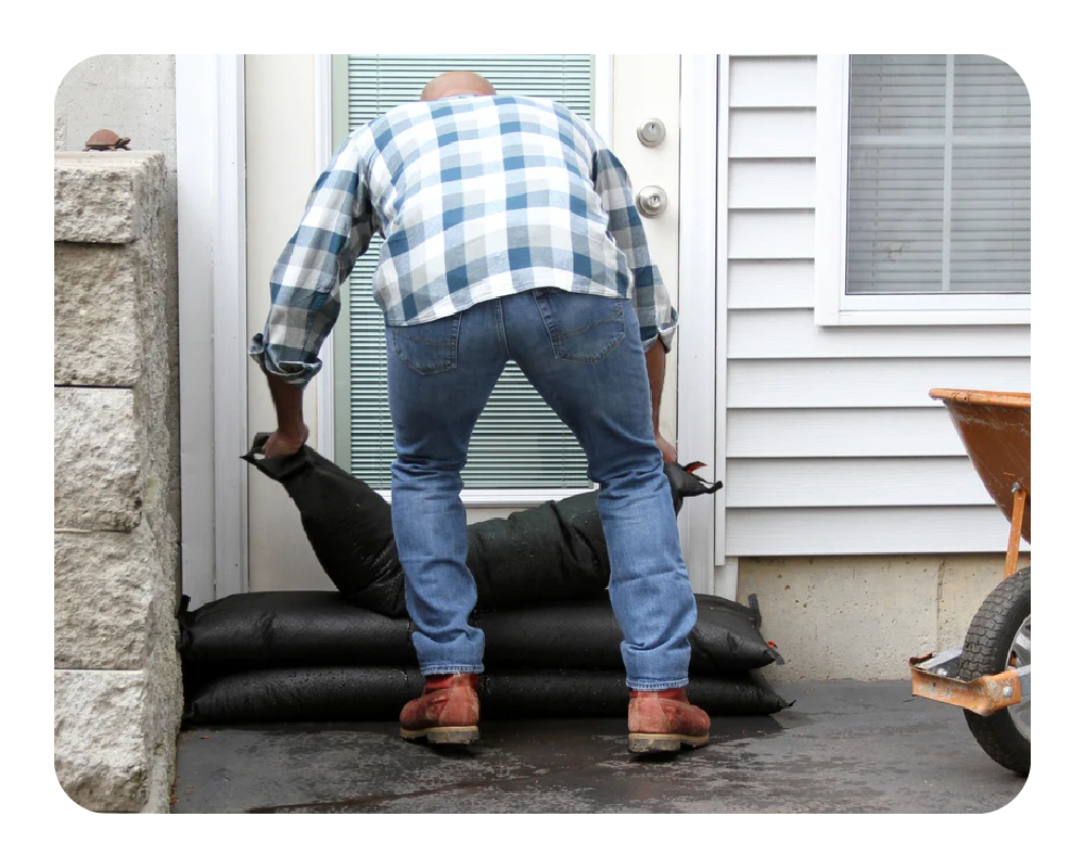 Person installing flood bags outside a house.