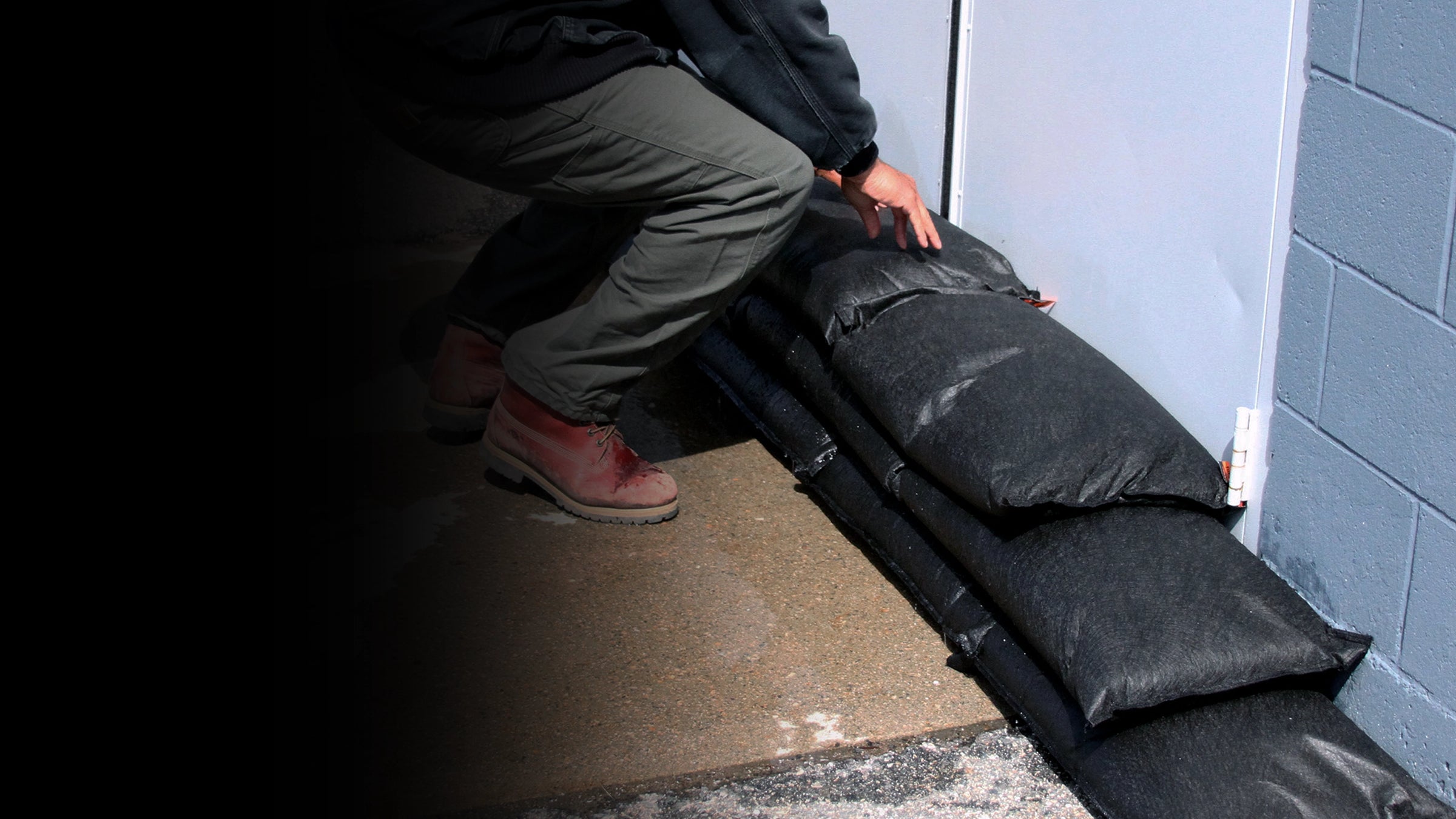 Person using a black flood bag to protect a door.