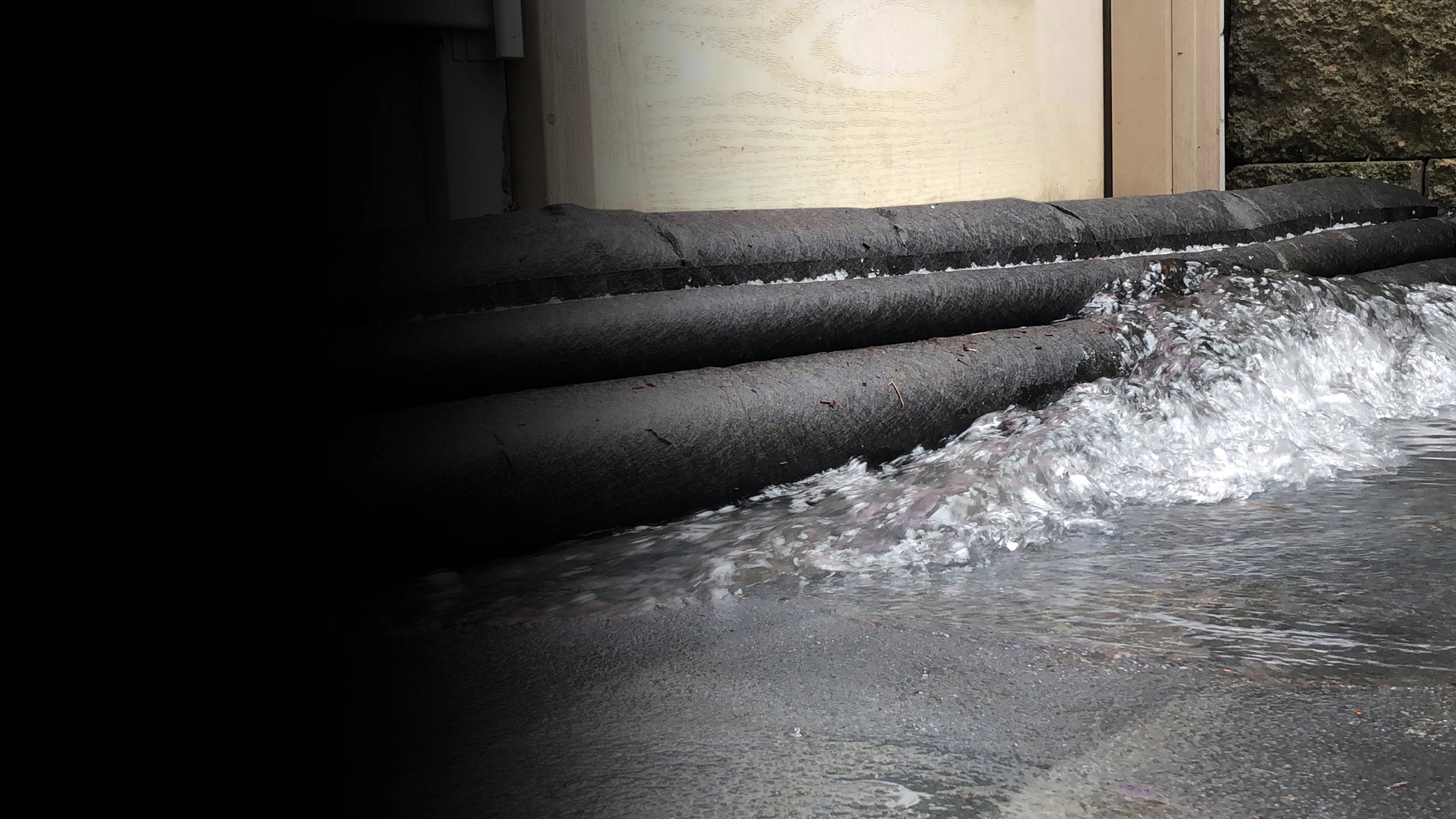 Water flowing up to flood barriers with a building in the background.