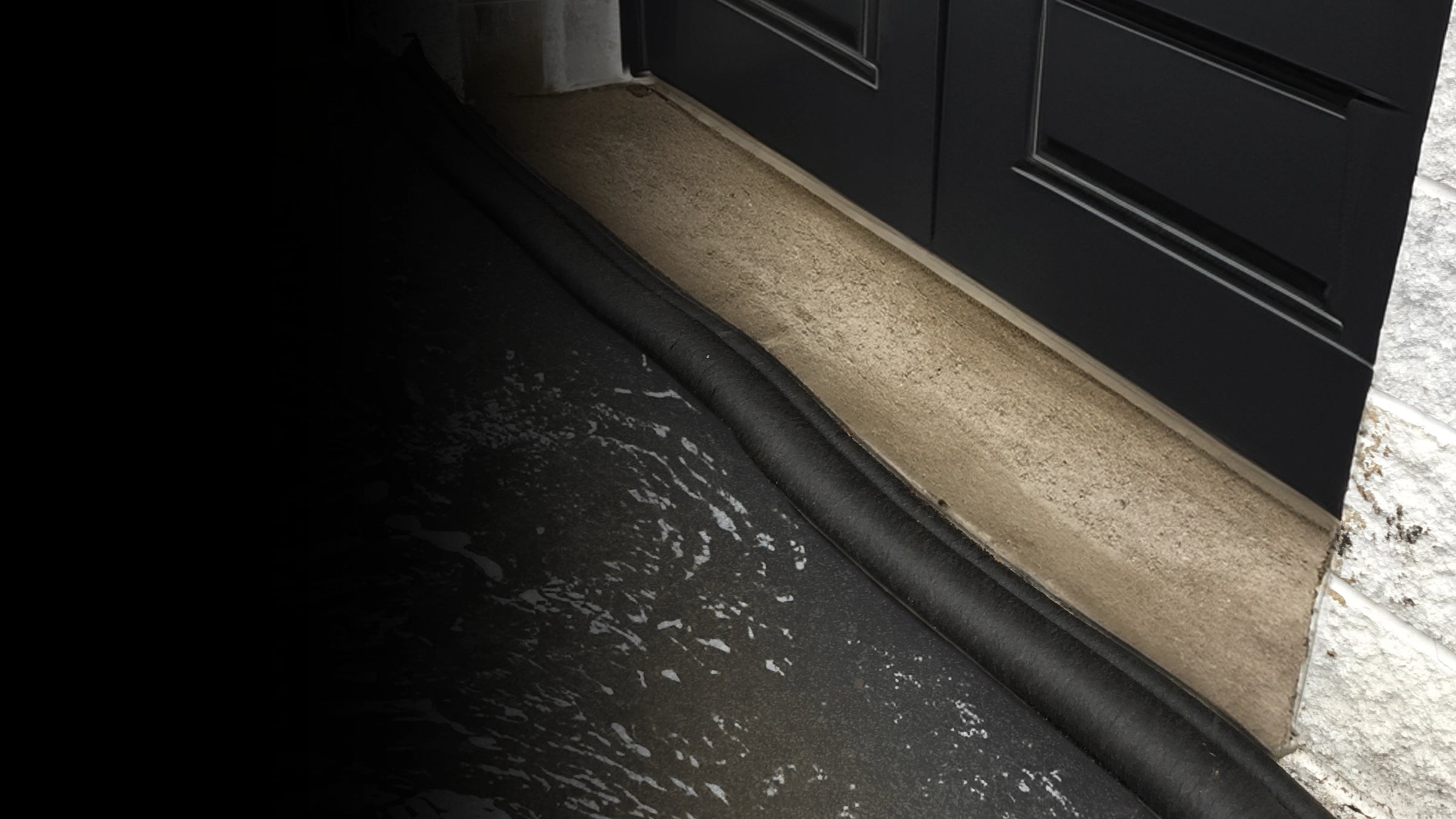 Close-up of a black garage door with flood barrier holding back water