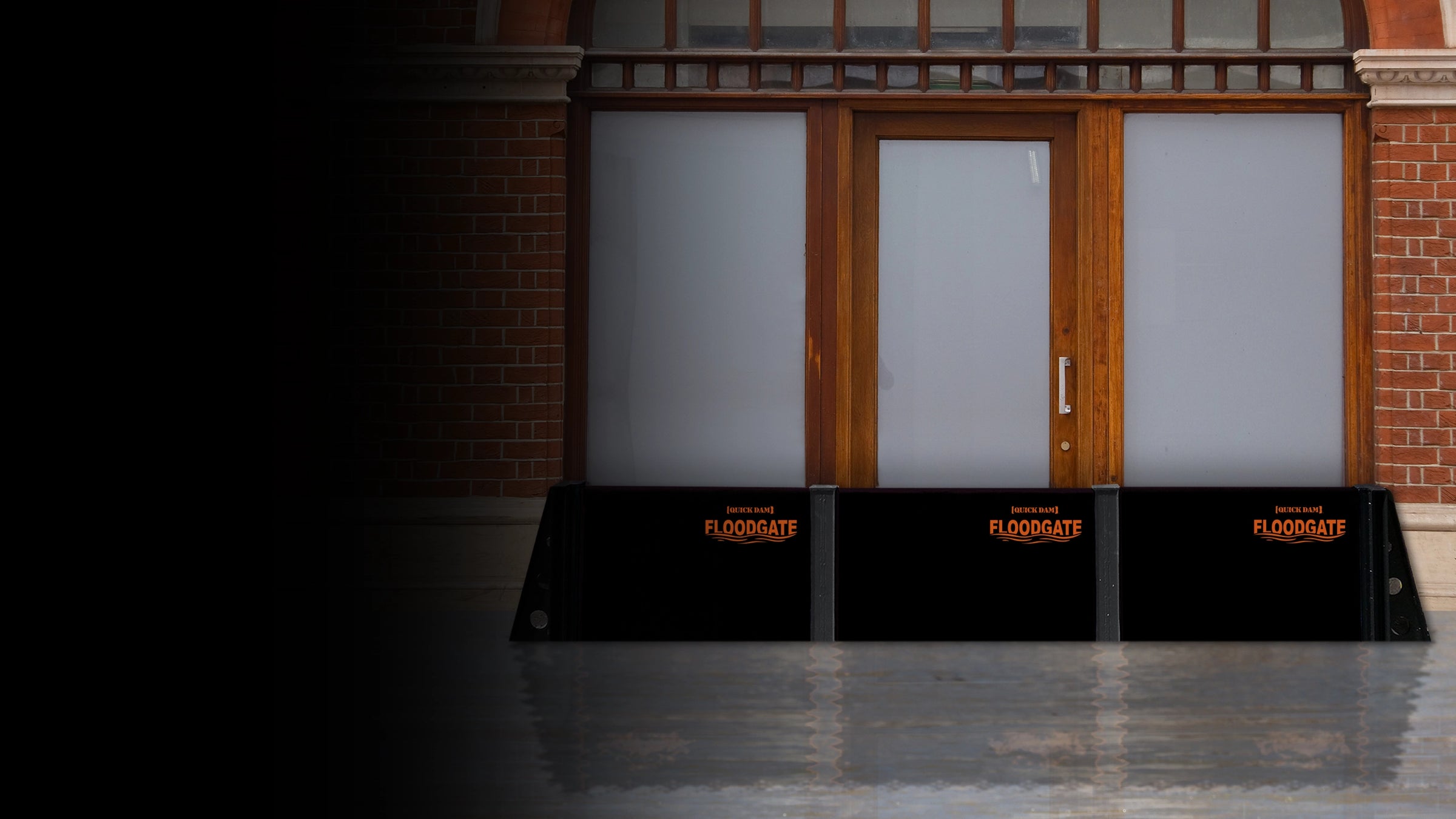 Black flood gates with orange text in front of a building entrance