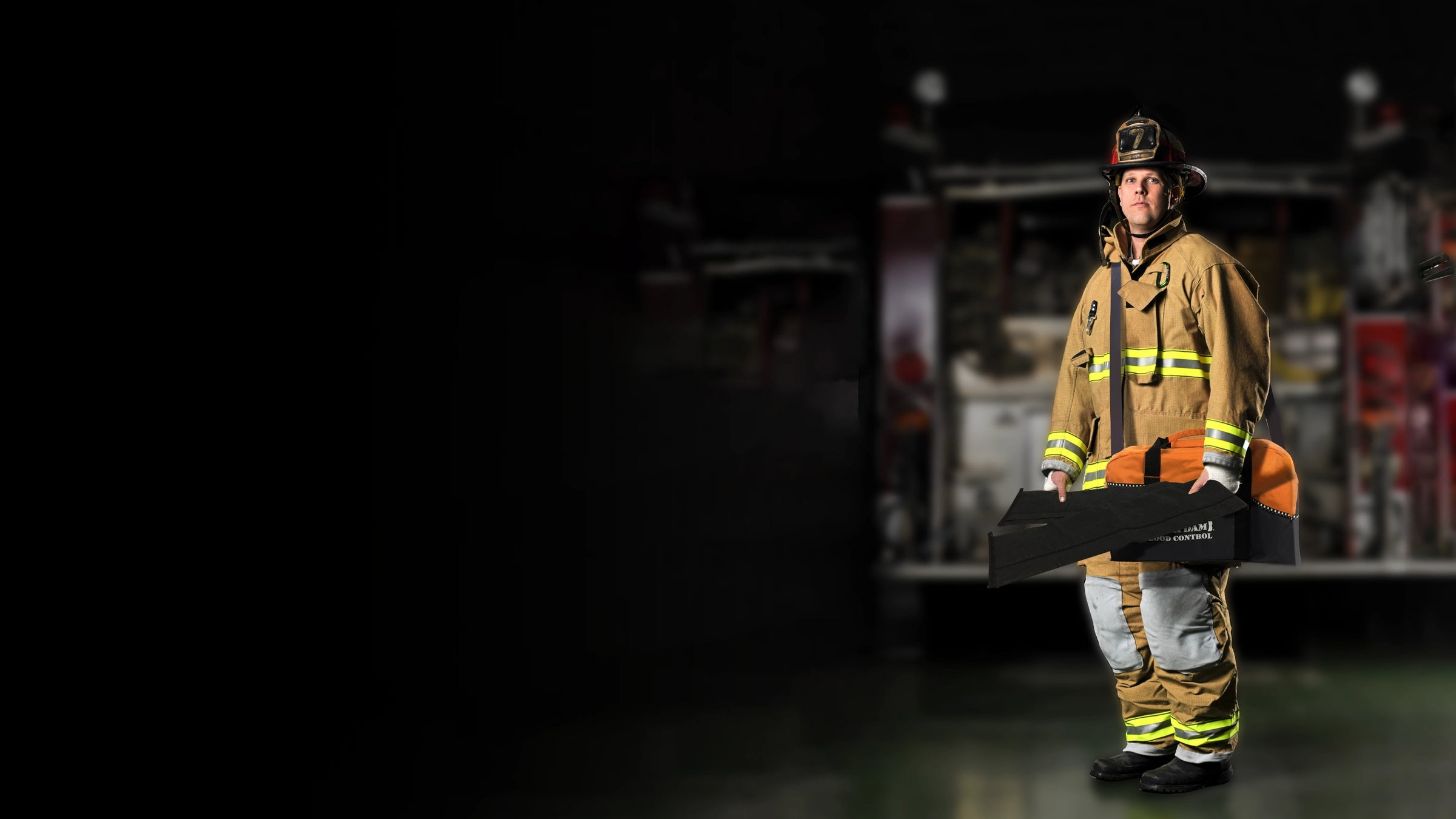 Firefighter in full gear holding a Quick Dam flood barrier