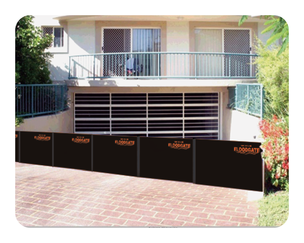 Black floodgates in front of a two-story building with balconies.