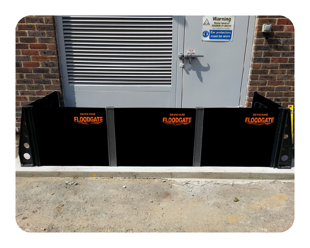 Black floodgate in front of a brick building with a gray door
