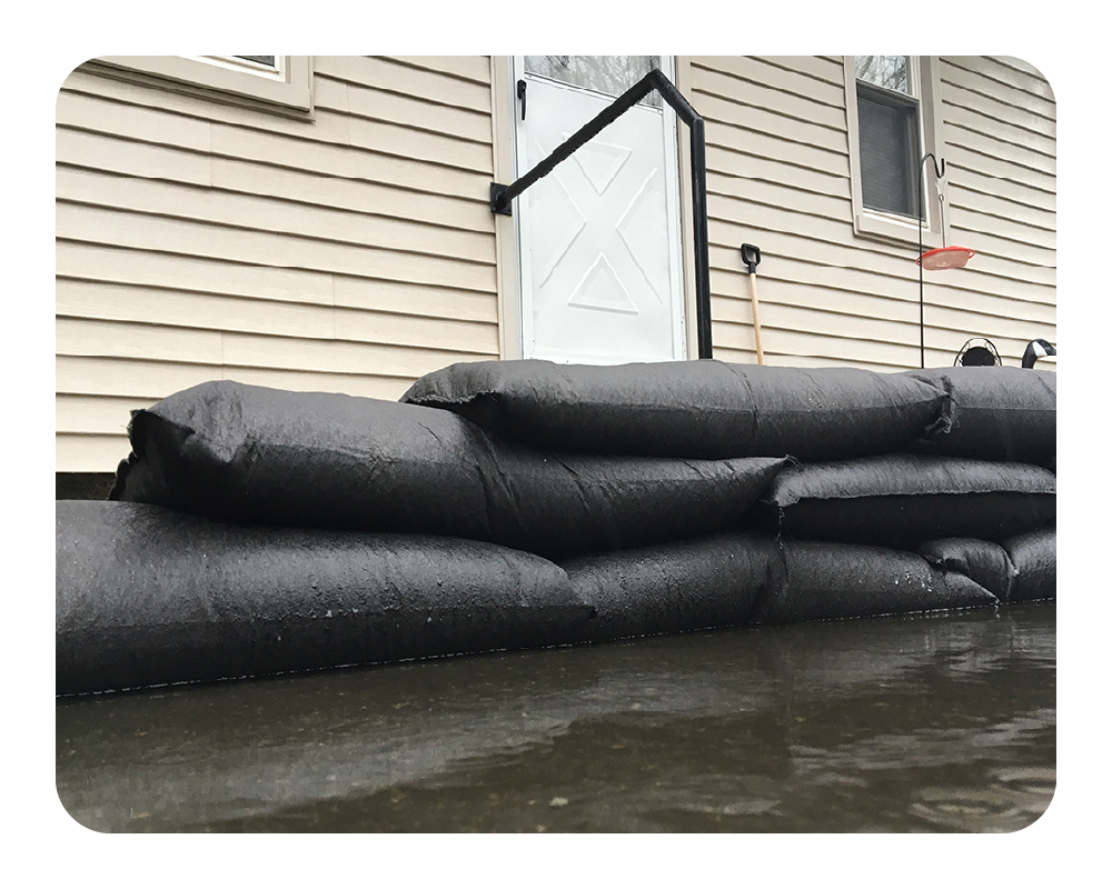 Stack of quick dam flood bags in front of a house during floodwaters