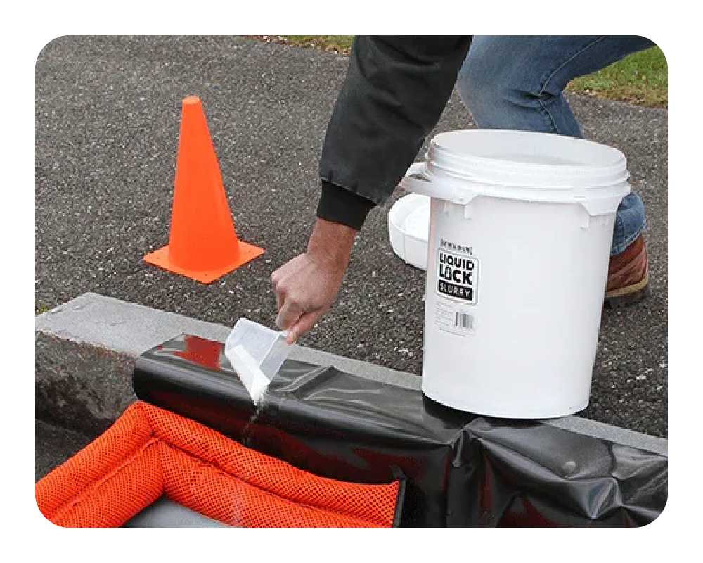Person applying liquid to a black surface with an orange cone and white bucket in the background.