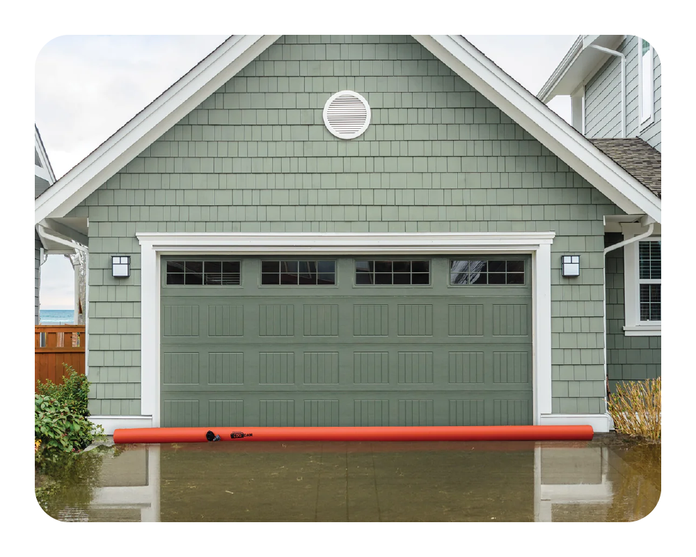 Green garage door on a house with a orange log dam in front holding back flood water