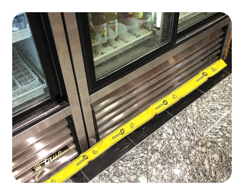Convenient store coolers with a yellow quick up on the floor to absorb water