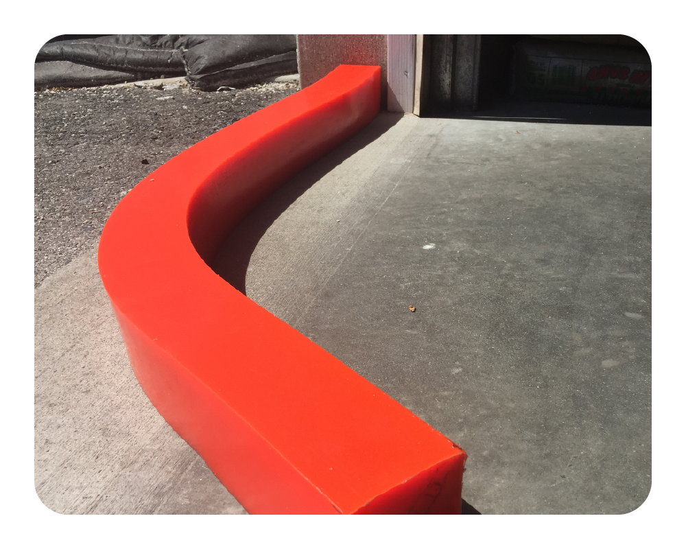 Orange curved insta-dam on gray pavement