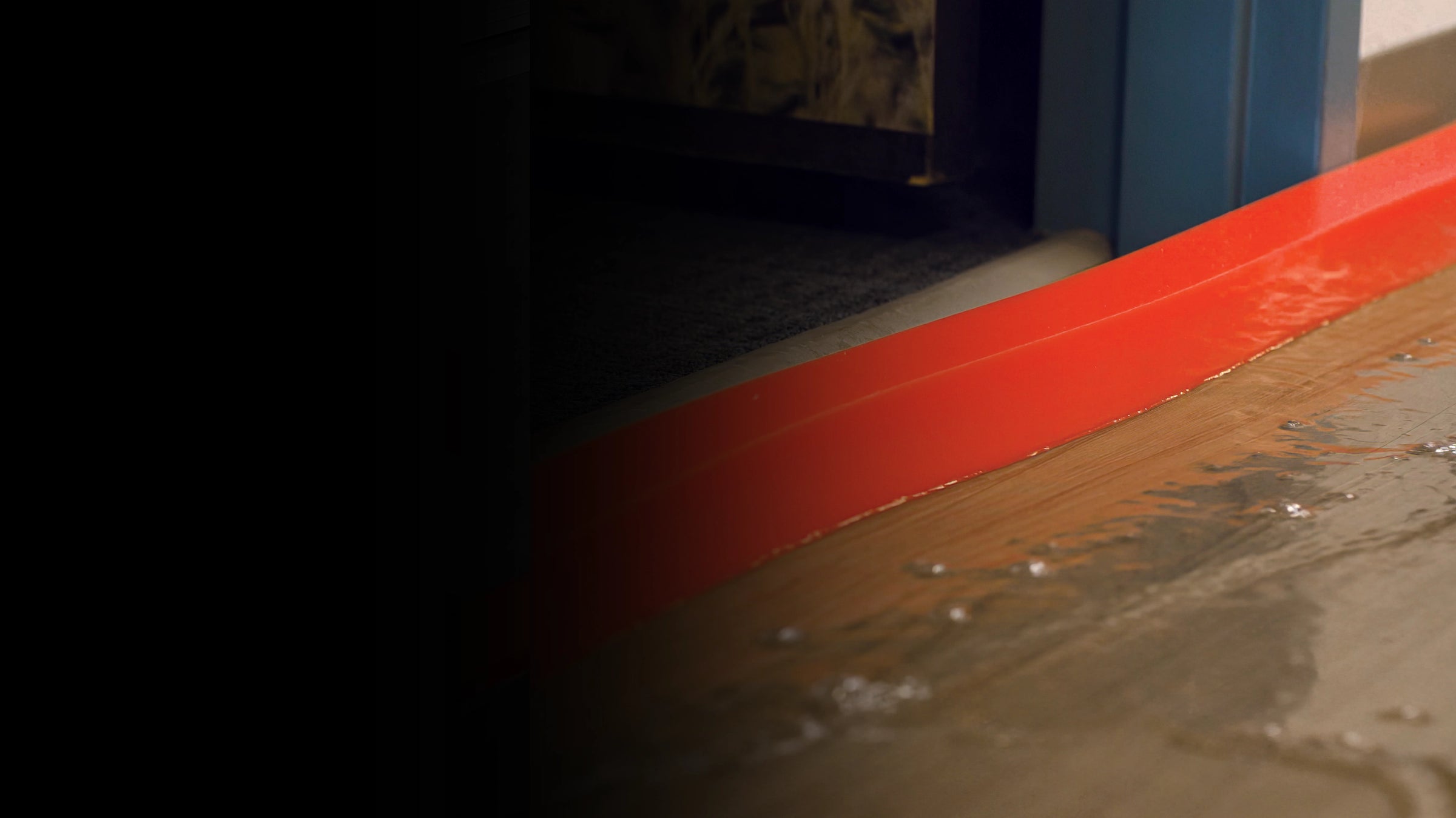 Close-up of a orange insta-dam on a wooden floor with a dark background