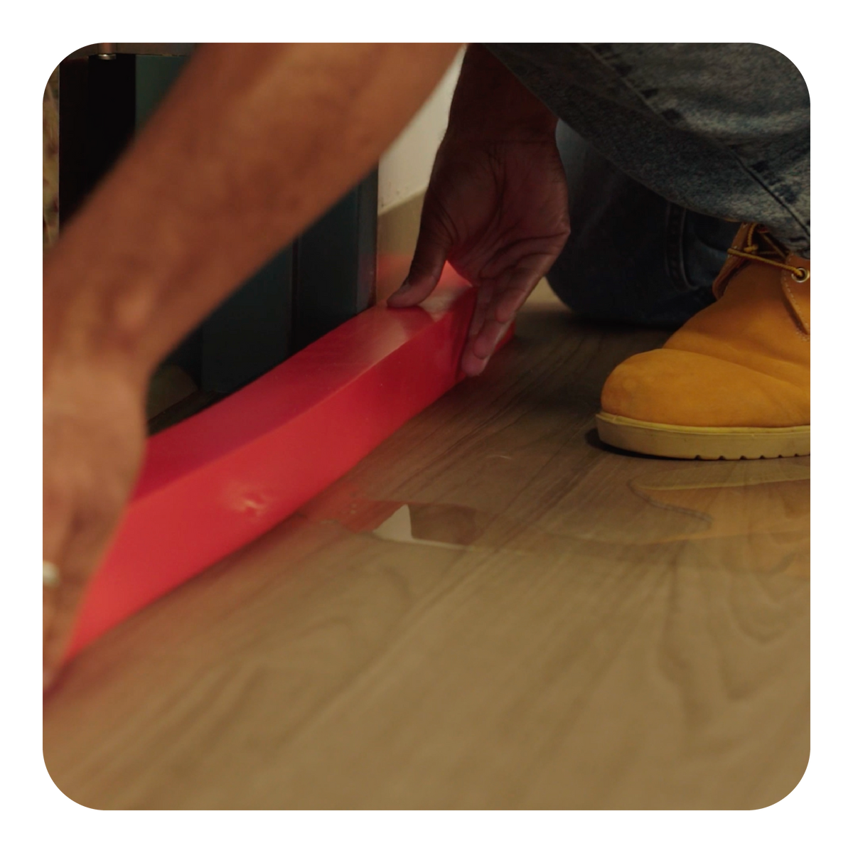 Person using an orange insta-dam on a wooden floor