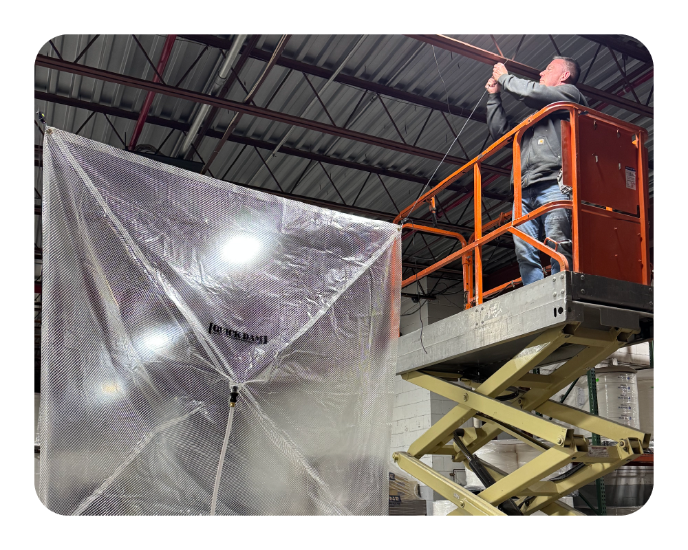 Person on a lift working with a large transparent leak diverter in an industrial setting