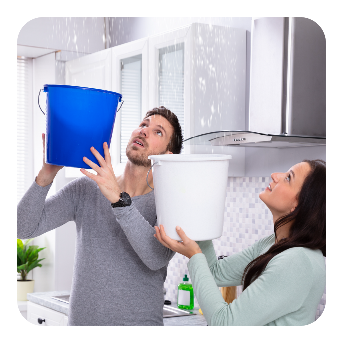 Two people holding buckets in a kitchen with water splashing around them.