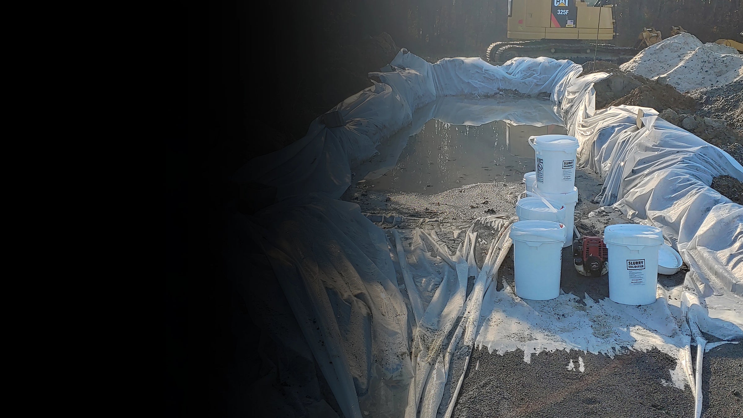 Construction site with white Liquid Lock buckets and a generator on a partially covered area