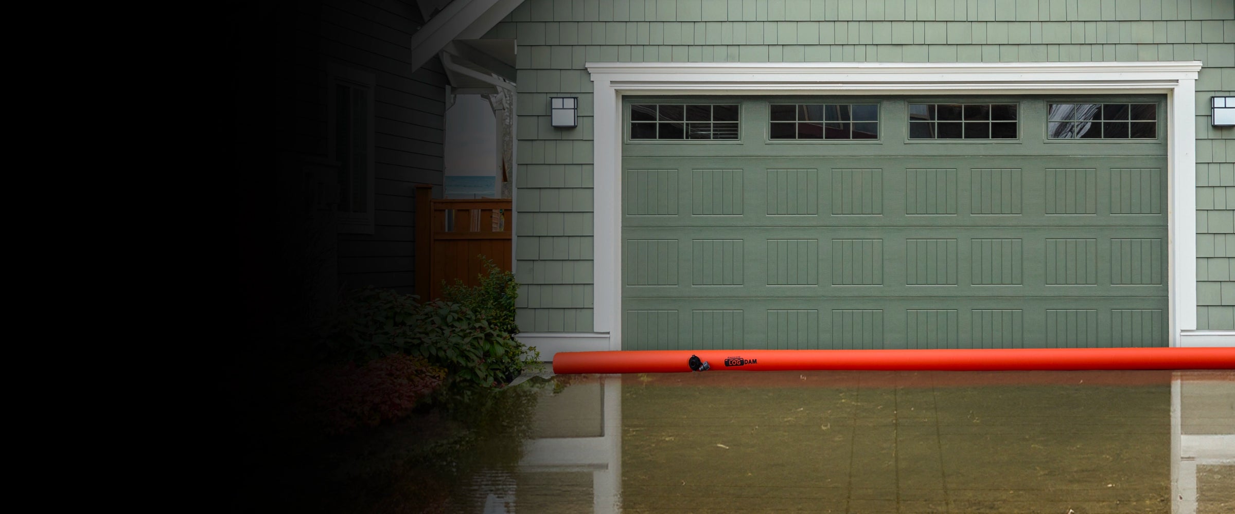 Orange Log Dam protecting a garage with water reaching the door, indicating a severe flood.