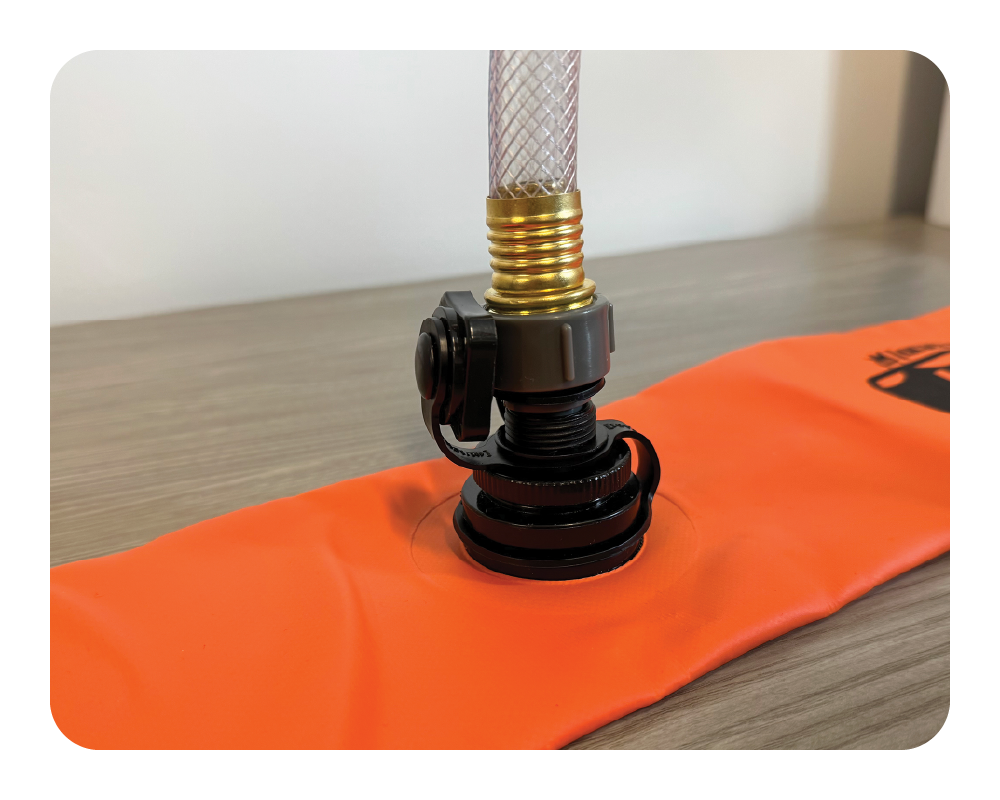 Orange log dam with a black valve and gold hose on a wooden surface.
